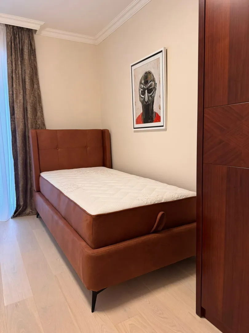 Bedroom with a brown upholstered bed and a wardrobe.