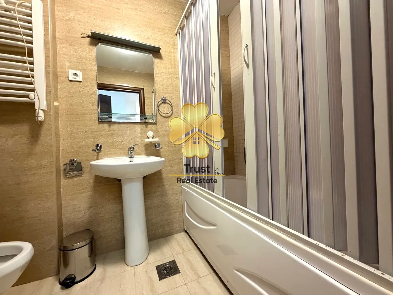 A clear bathroom with a sink, mirror, and bathtub with a screen.