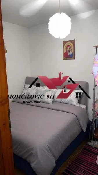 Manja spavaća soba sa bračnim krevetom i visećom lampom.