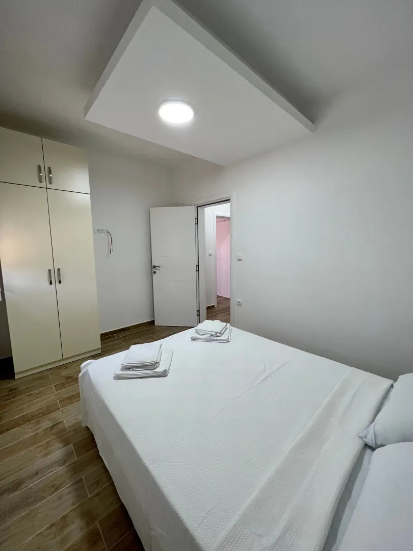 Bedroom with a double bed, wardrobe, and white linens.