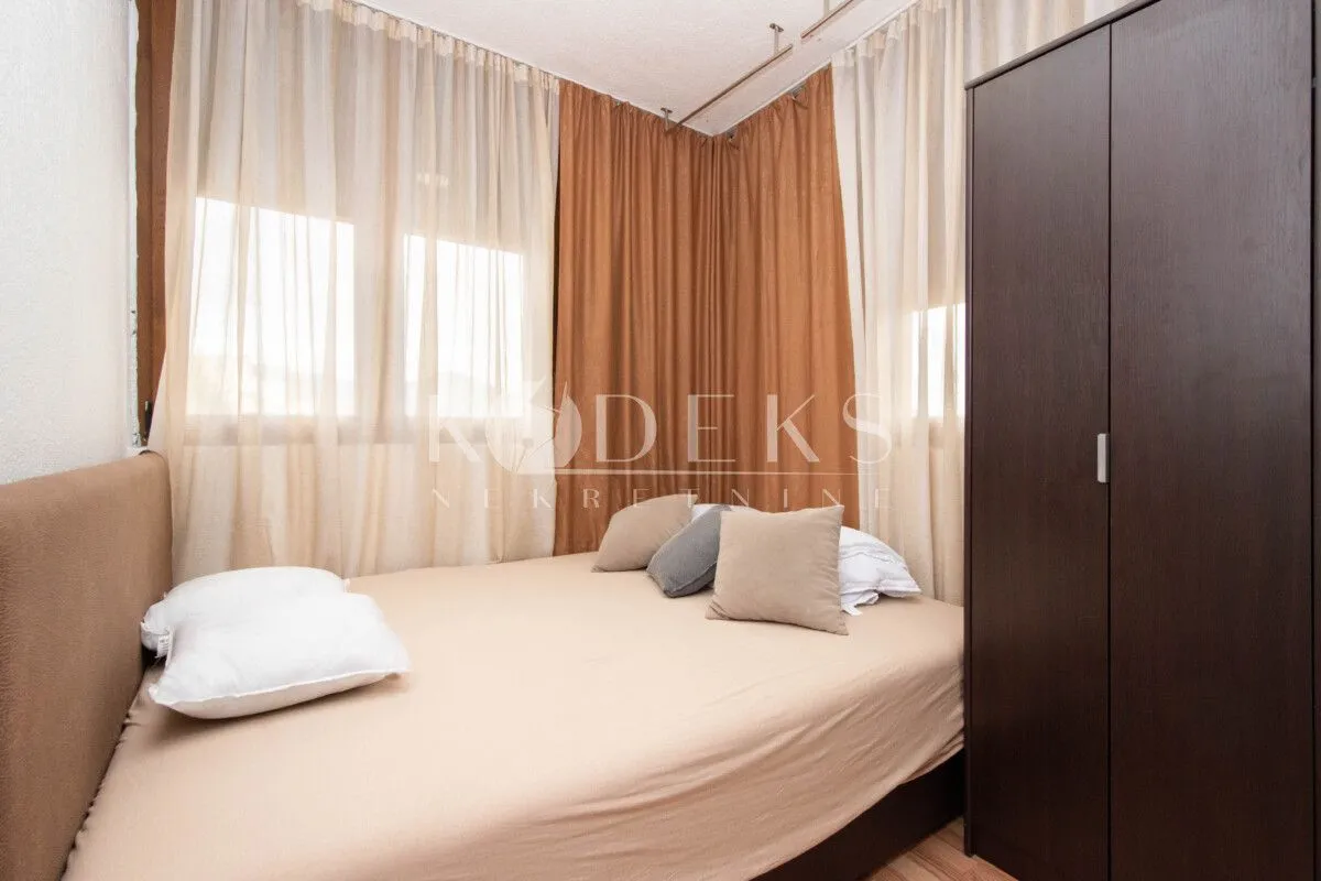 Furnished bedroom with a double bed, wardrobe, and curtains on the windows.