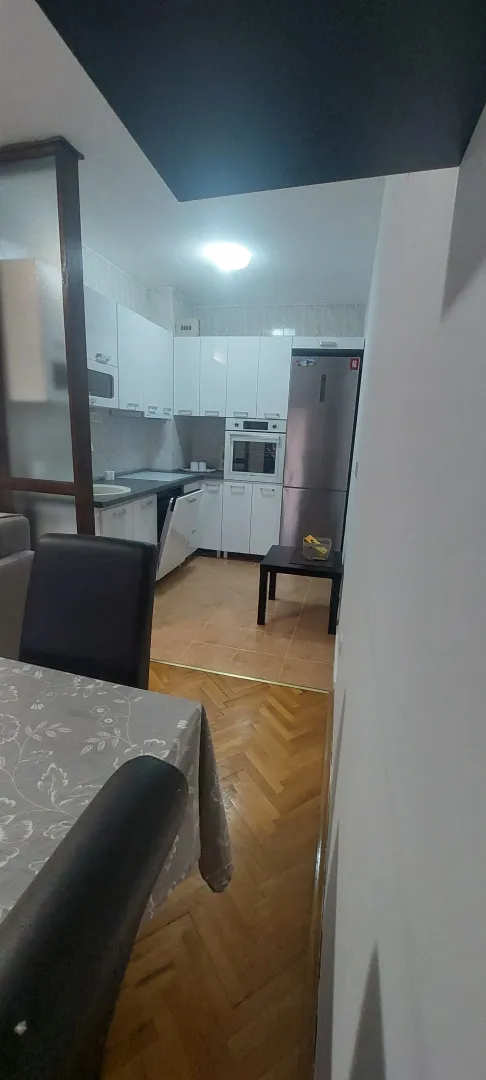 Pogled iz trpezarije prema kuhinji sa bijelim elementima.