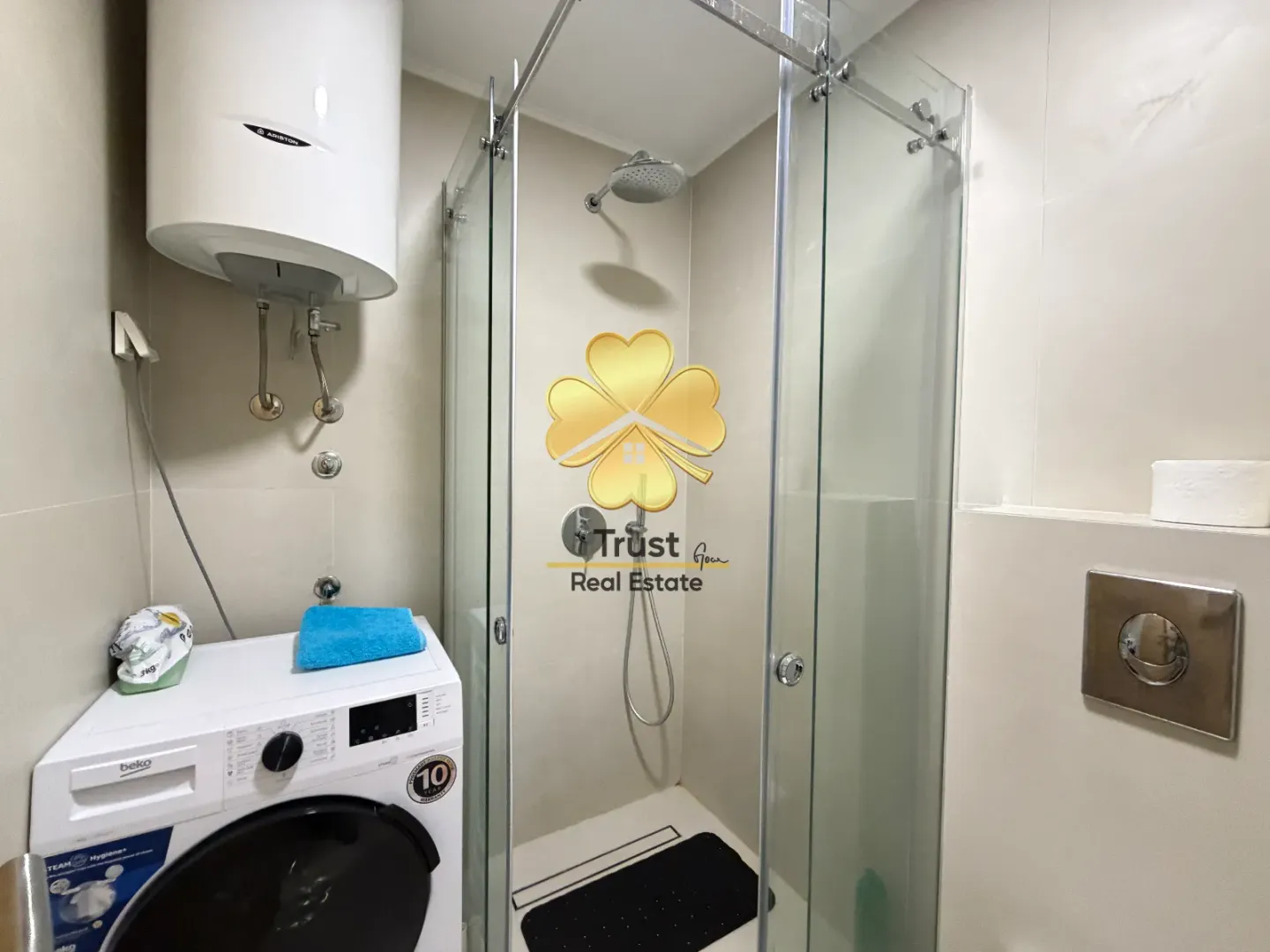 Smaller bathroom with a shower cabin, water heater, and washing machine.