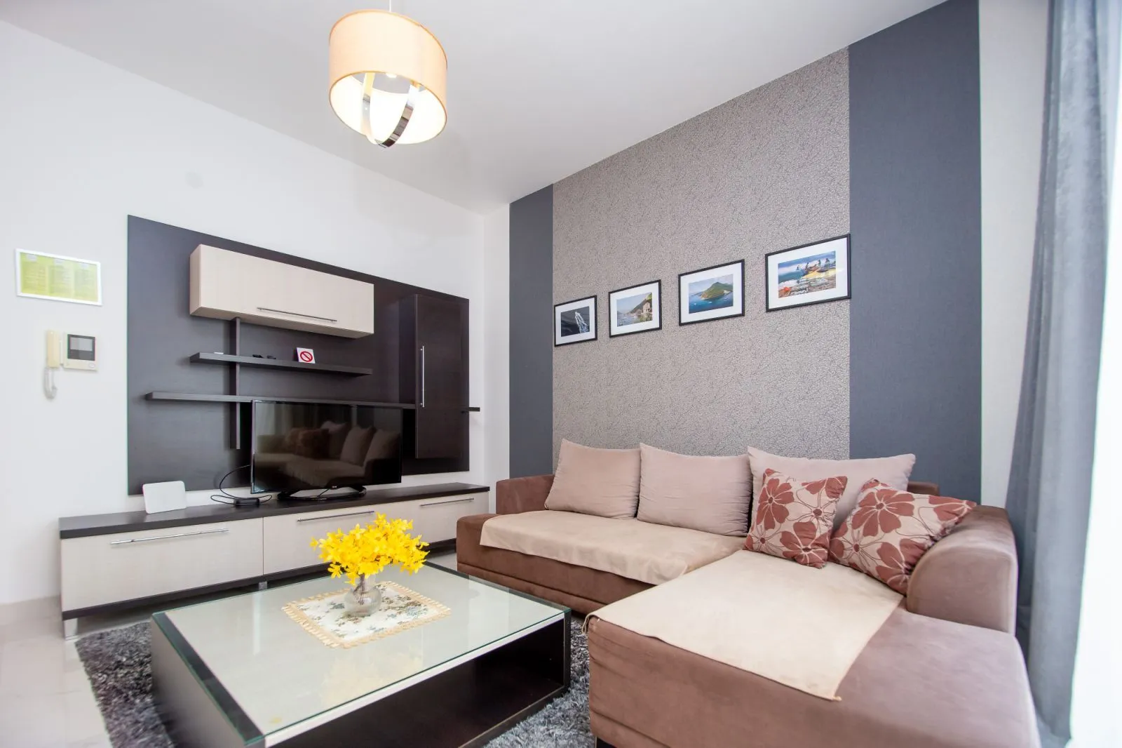 Furnished living room with a sectional sofa, TV unit, and decorative details.