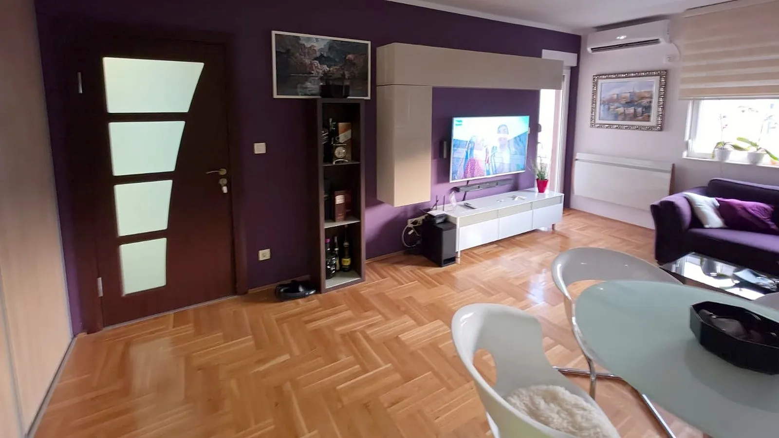 Dnevna soba sa garniturom, televizorom i trpezarijskim stolom.