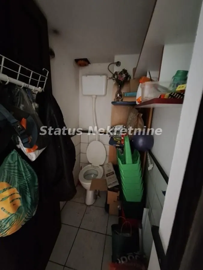 Small bathroom with a toilet and storage shelves.