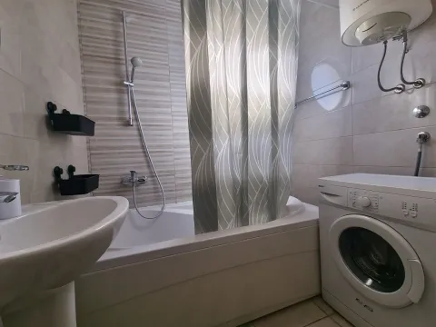 Bathroom equipped with a bathtub, washbasin, and washing machine. - image 3