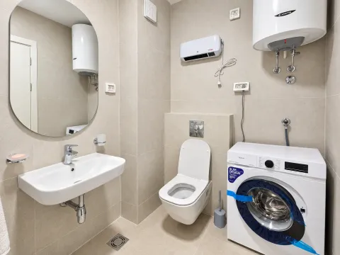 Bathroom equipped with a washbasin, toilet, water heater, and washing machine. - image 8