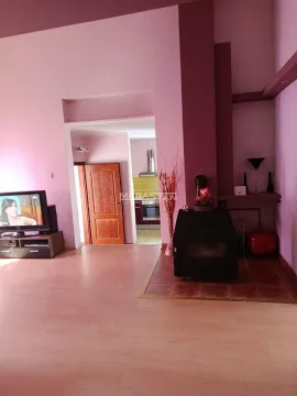 Living room with a fireplace and a view of the kitchen in the background. - image 6