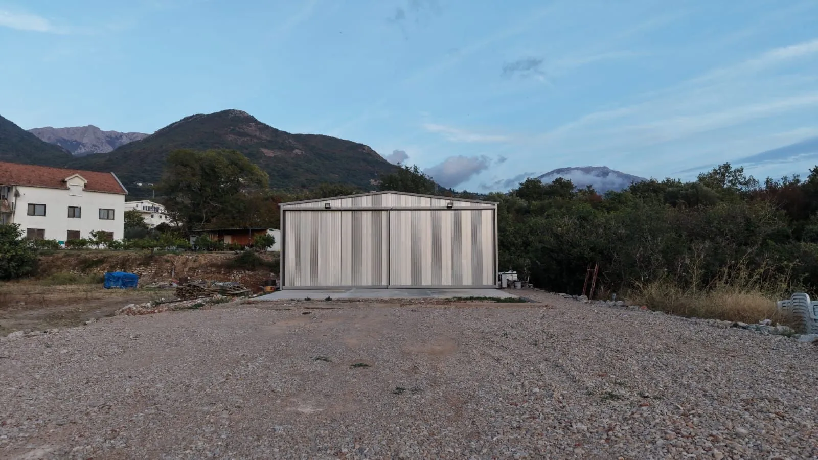 Prefabricated warehouse with a yard and mountain view.