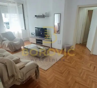 Nameštena dnevna soba sa garniturom, televizorom i parketom na podu. - image 2