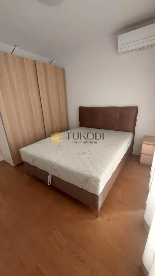 Bedroom with a double bed, wooden wardrobe and air conditioning unit.