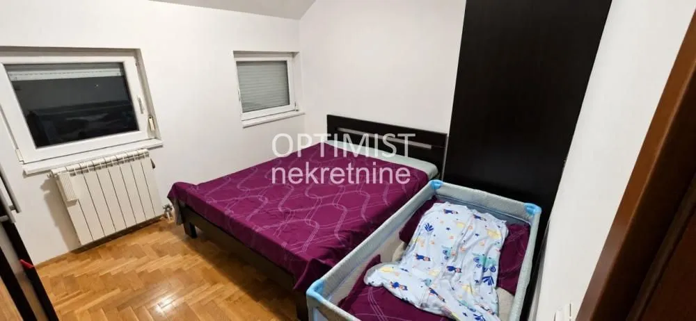 Spavaća soba sa bračnim krevetom i krevetcem za bebe.