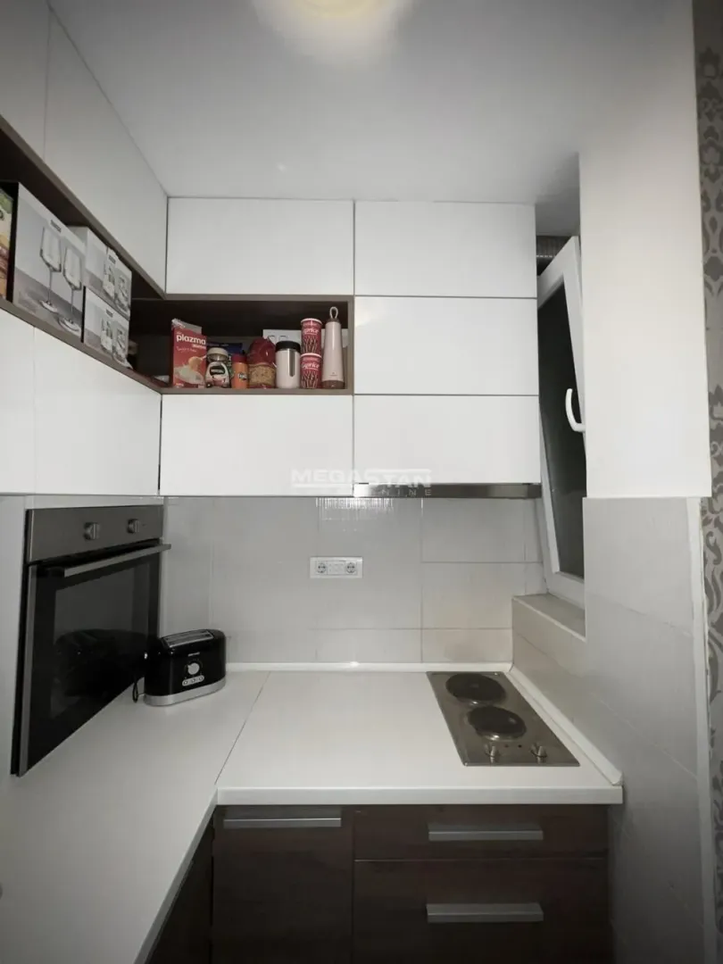 Small kitchen with white units and a built-in oven.