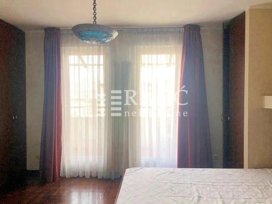 Bedroom with a bed, windows, and dark curtains.