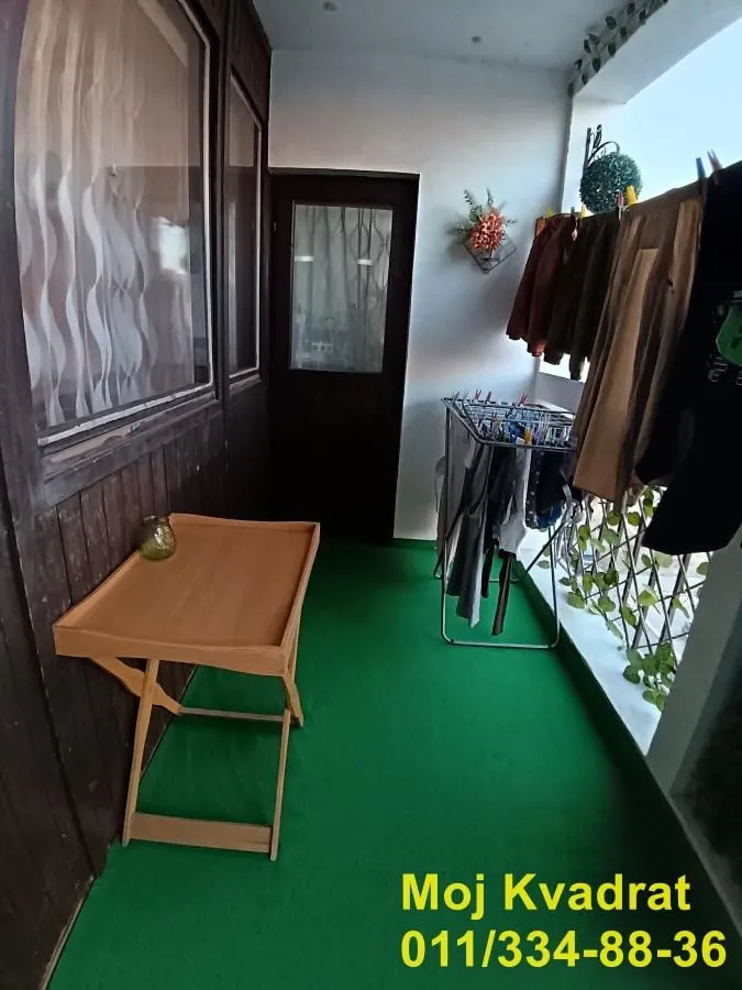 Natkriveni balkon sa veštačkom travom na podu i sušilicom za veš.