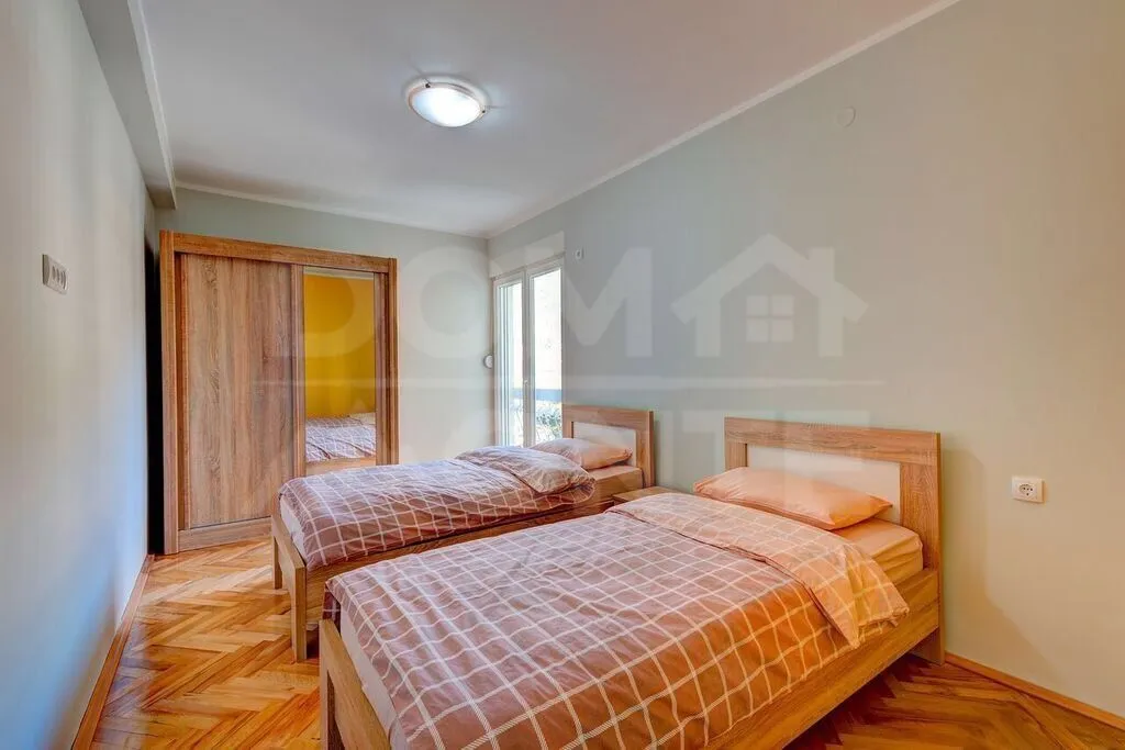Furnished bedroom with two single beds and a wooden wardrobe.