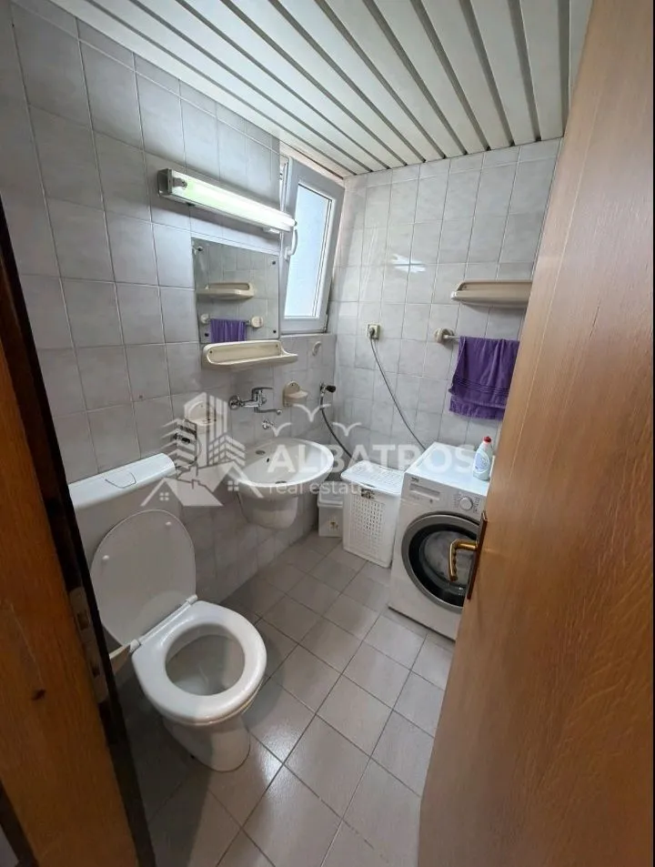Bathroom with a toilet, washbasin, mirror, and washing machine.