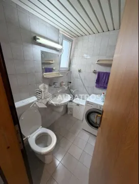 Bathroom with a toilet, washbasin, mirror, and washing machine. - image 4