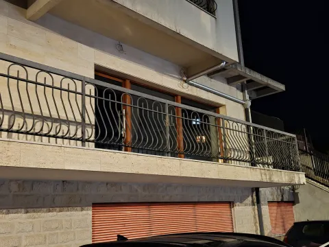 View of the building exterior with a balcony and wrought iron railings at night. - image 6