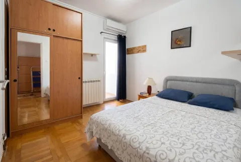 Namještena spavaća soba sa bračnim krevetom, velikim drvenim ormarom i izlazom na terasu. - image 4
