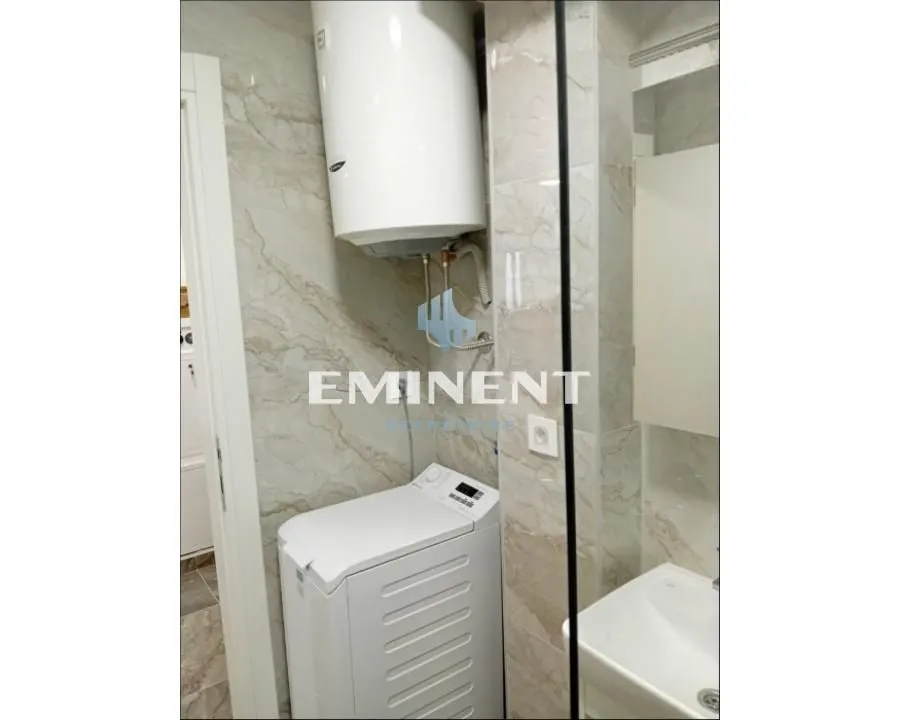 Bathroom with a washing machine, boiler, and washbasin tiled with marble.