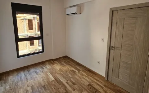Prazna soba sa drvenim podom, klima uređajem i prozorom. - image 6