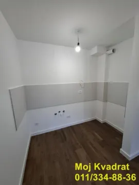 Prazna prostorija sa pripremljenim priključcima za kuhinju i drvenim podom. - image 3