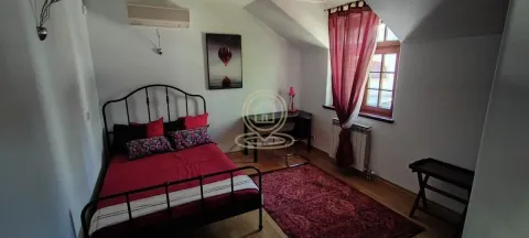 Furnished bedroom with a double bed, desk, and a window with red curtains. - image 13