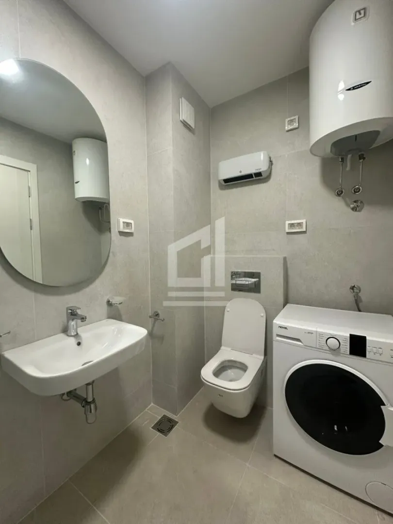 Savremeno opremljeno kupatilo sa umivaonikom, WC šoljom, veš mašinom i bojlerom.