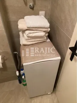 Manje kupatilo sa veš mašinom i složenim peškirima. - image 7