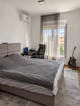 Furnished bedroom with a double bed, desk, and guitar. - image 6