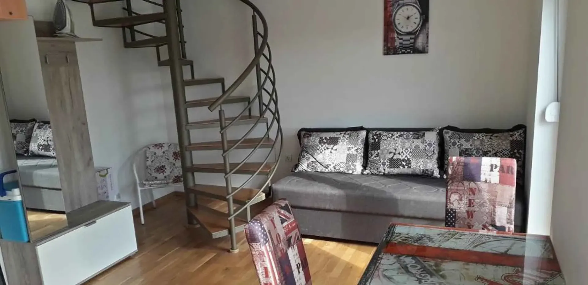 Dnevni boravak sa garniturom, trpezarijskim stolom i spiralnim stepeništem.