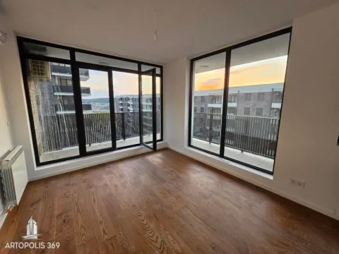 Empty room with wooden flooring and large windows overlooking surrounding buildings. - image 5