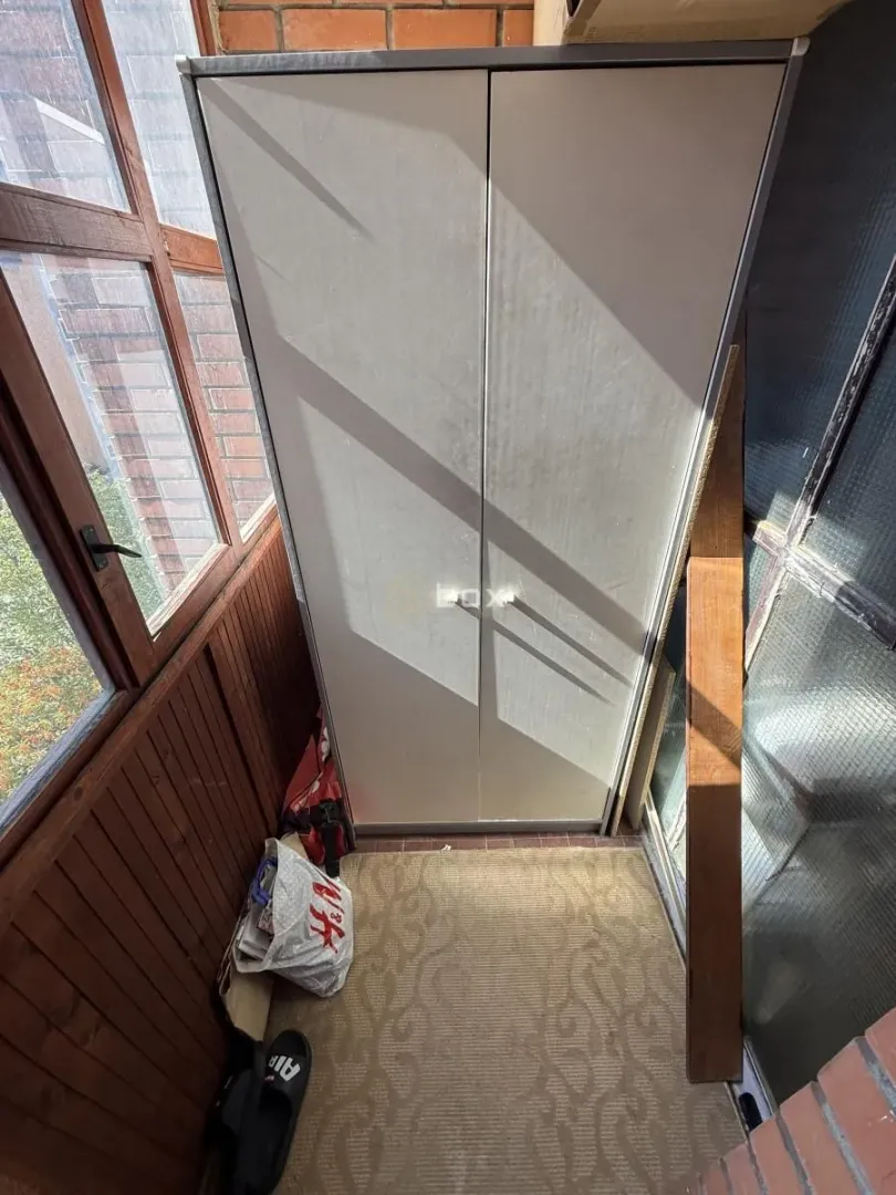 Enclosed balcony with a wardrobe and wooden paneling.