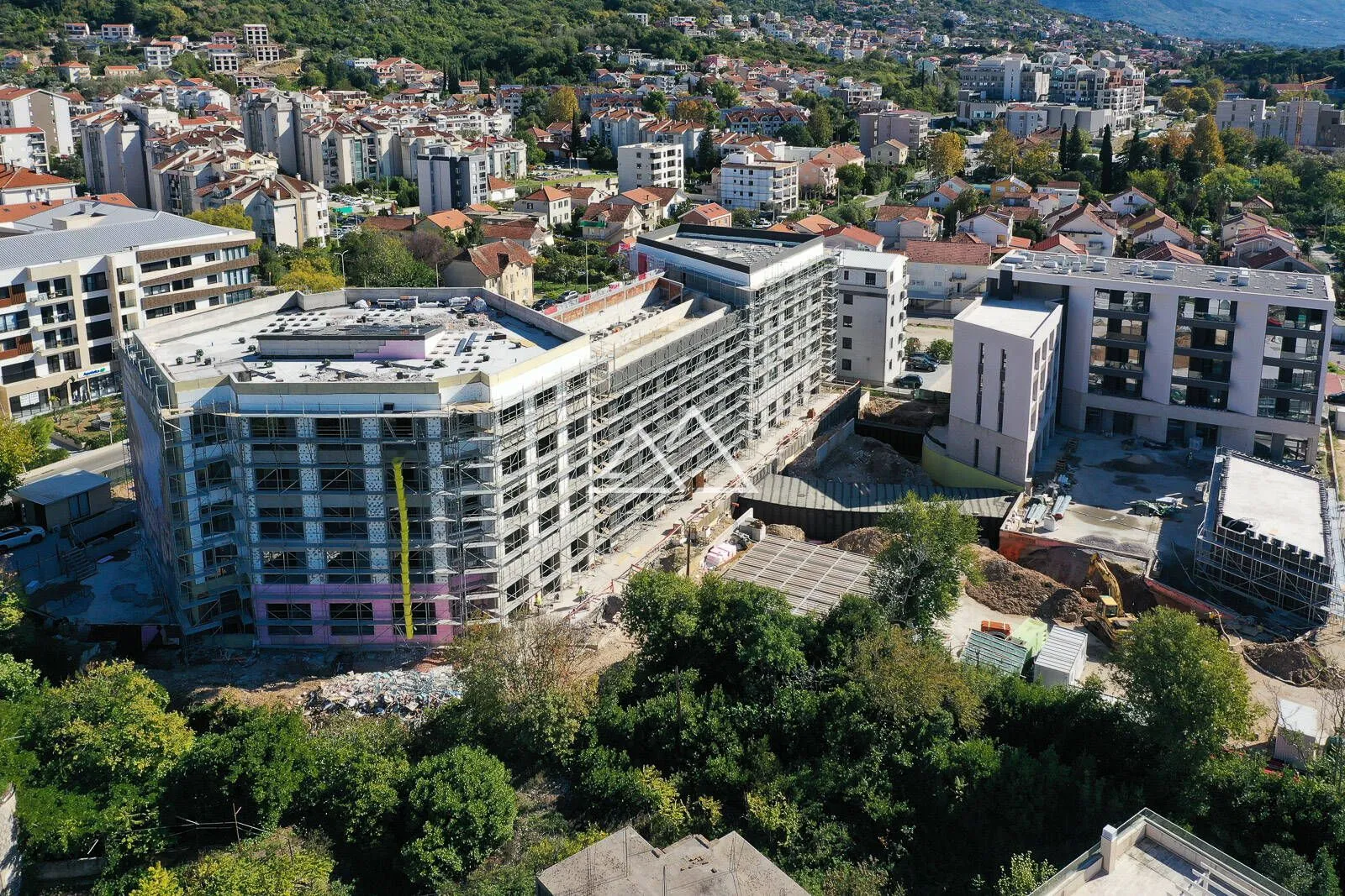 Pogled iz vazduha na stambeni objekat u izgradnji okružen gradskim naseljem.