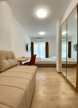 Bedroom with a bed, sofa, desk, and large mirror. - image 9