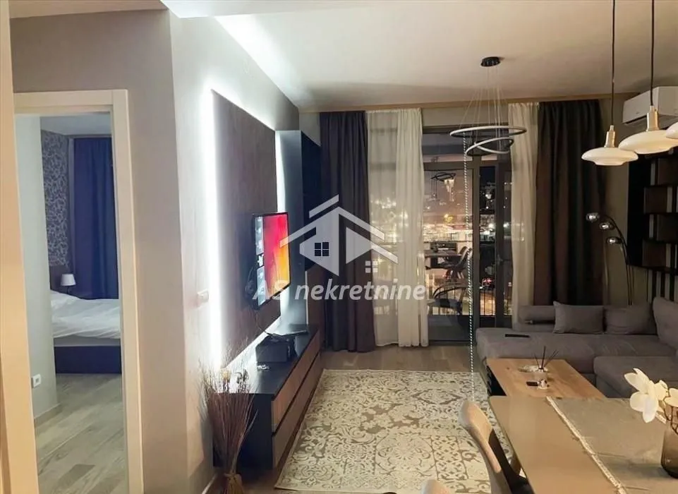 Living room with sofa, TV and dining table.
