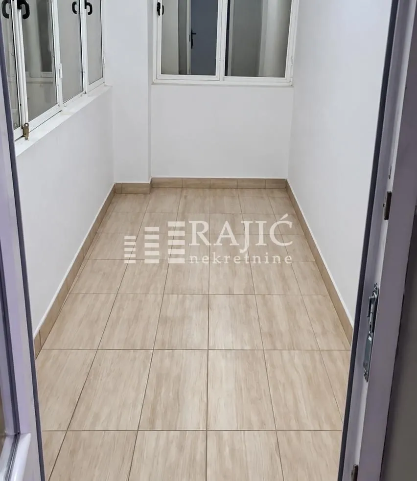 Empty enclosed balcony with ceramic floor tiles.