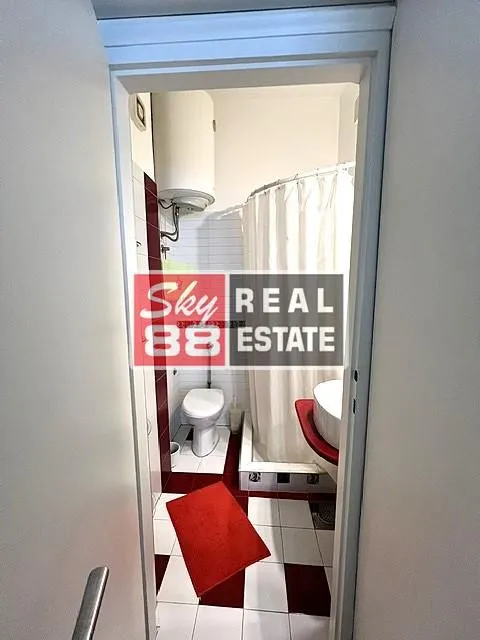 Pogled iz hodnika na kupatilo sa tuš kabinom i wc šoljom.