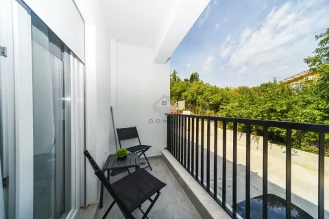 Manji svijetli balkon sa crnim stolom i stolicama i pogledom na zelenilo. - image 11