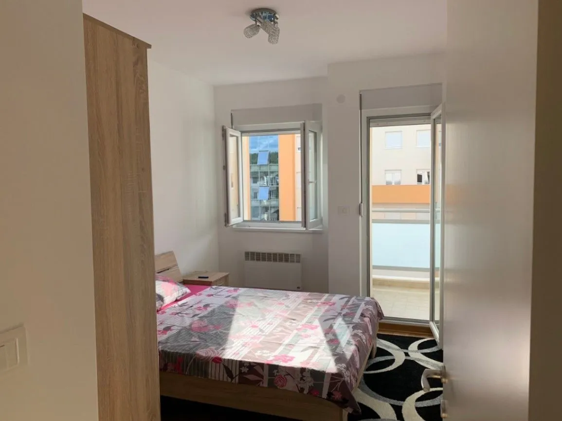 A bright bedroom with a double bed, wardrobe, and access to a balcony.