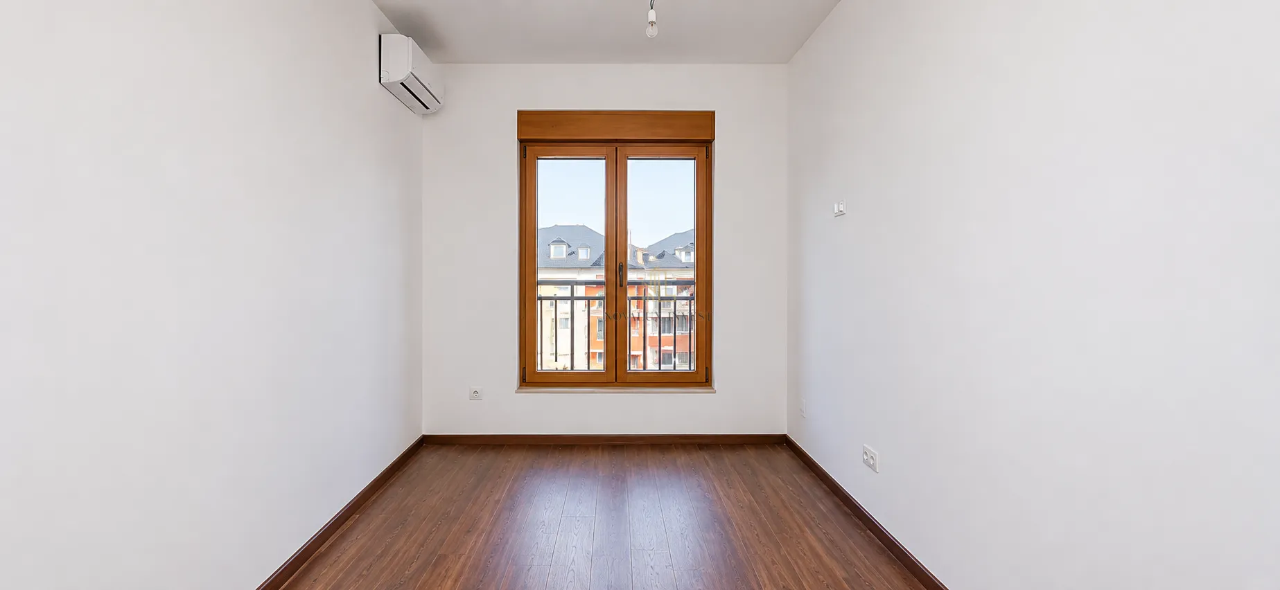 Empty room with white walls, wooden floor, and a window.
