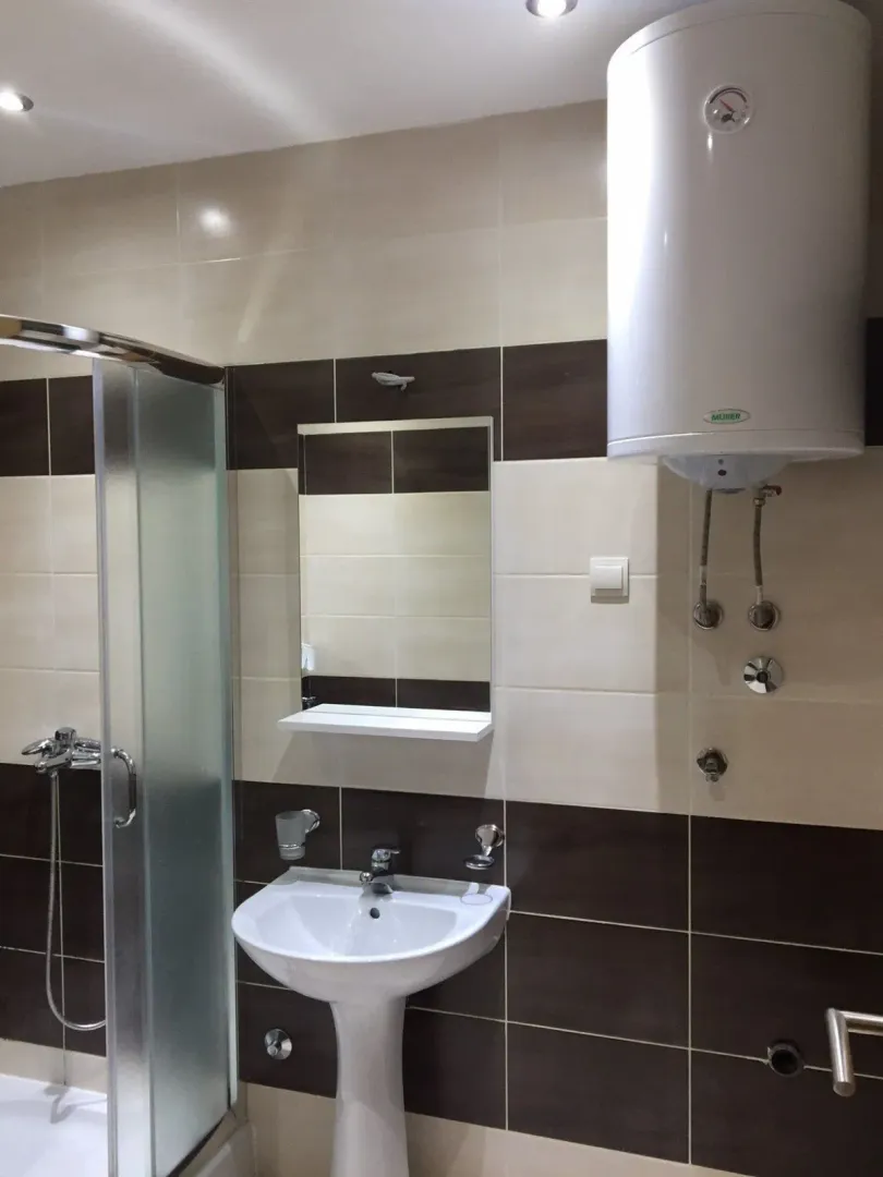 Bathroom equipped with a washbasin, shower cabin, and water heater.