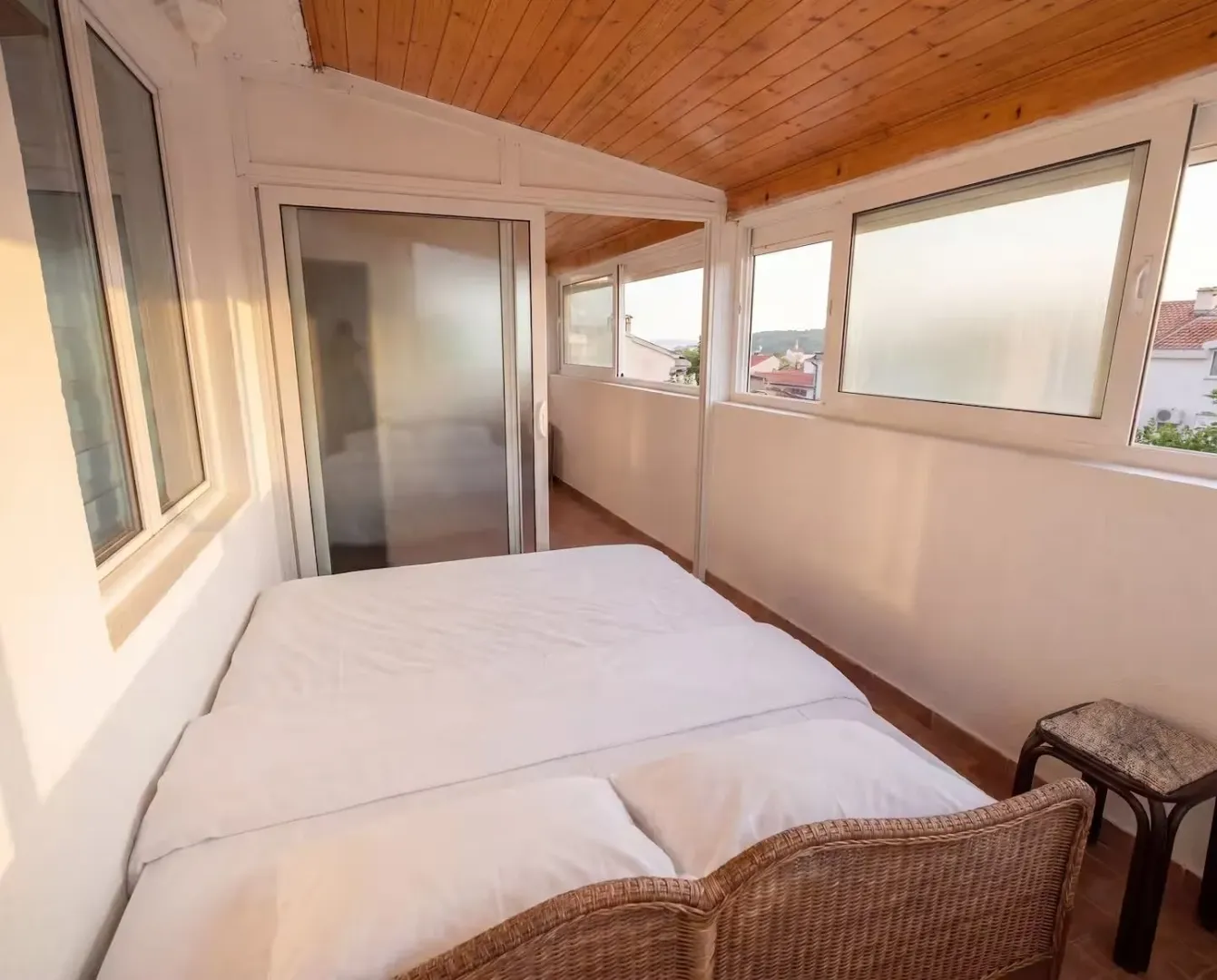 Enclosed terrace furnished as a bedroom with a double bed.