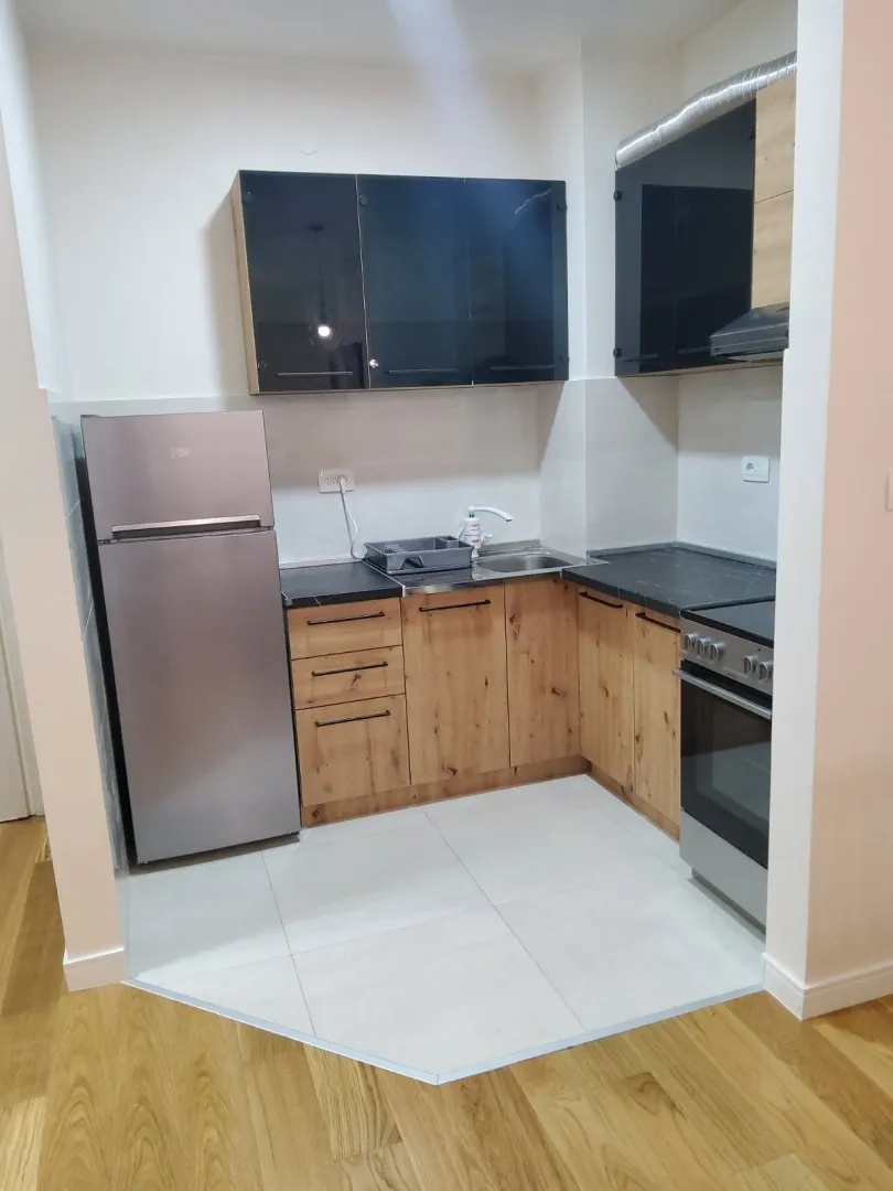Small kitchen with wooden lower cabinets, black upper cabinets and appliances.