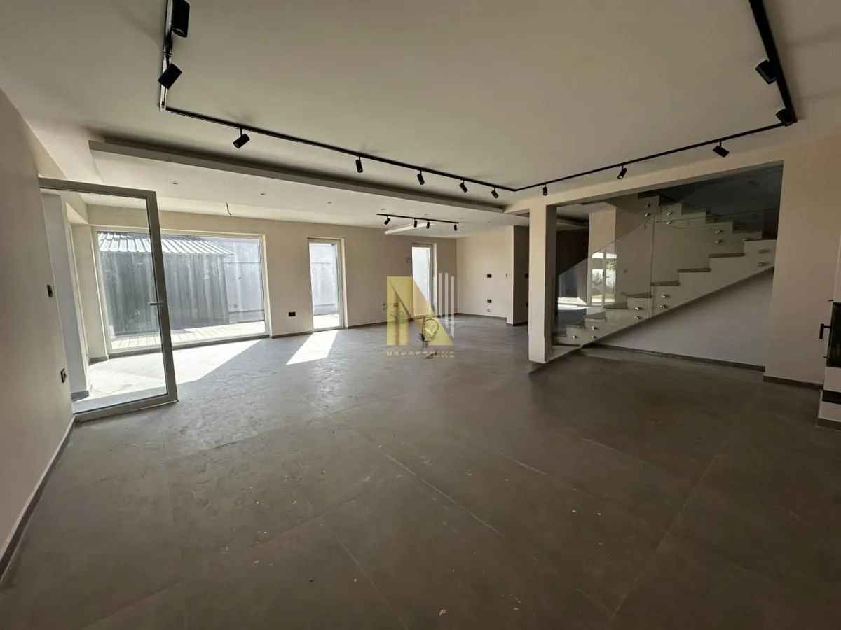 Spacious unfurnished living room with staircase and modern lighting.