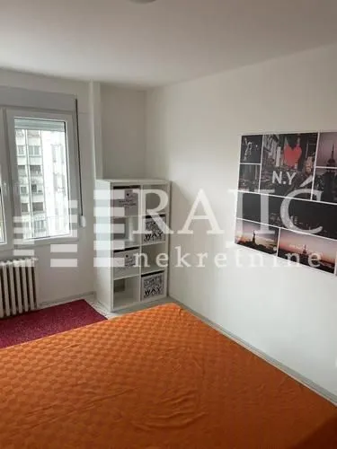 Small bedroom with a double bed, white shelving unit, and a window.
