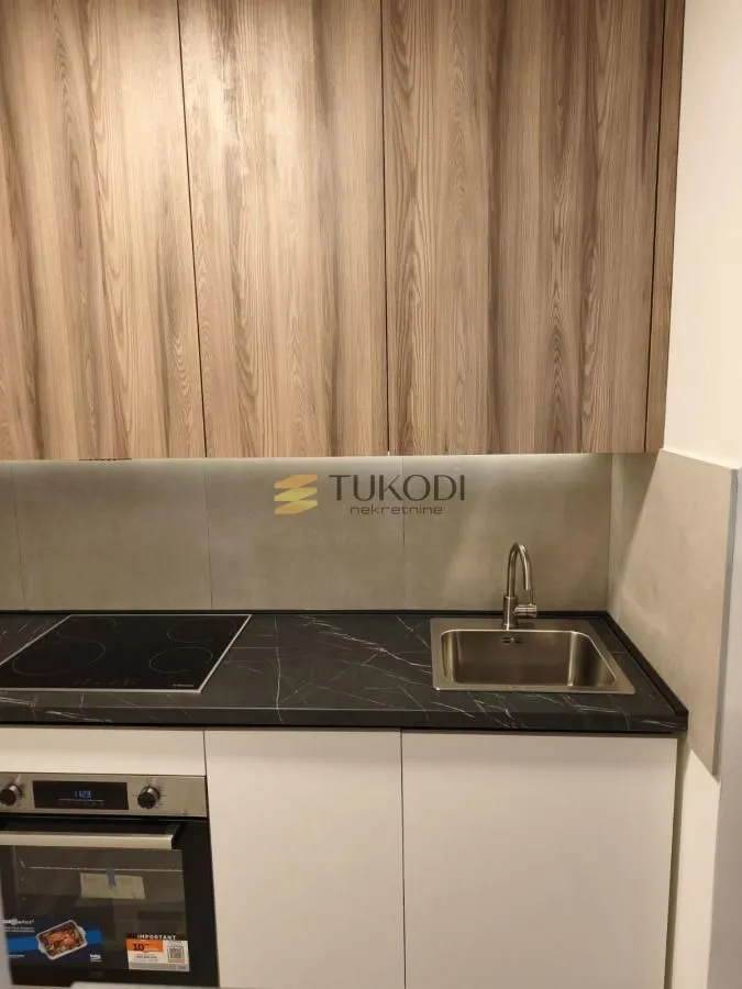 Part of the kitchen with built-in oven, hob, sink and wooden cabinets.