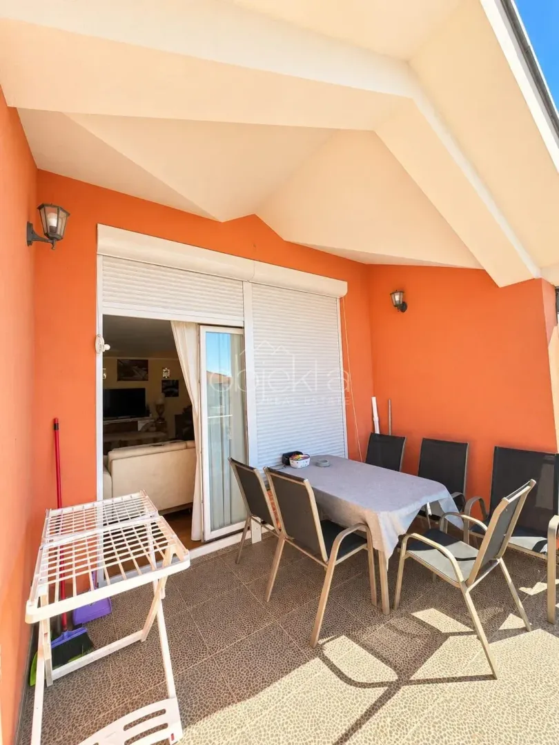 Covered terrace with a table, chairs, and a clothes drying rack.